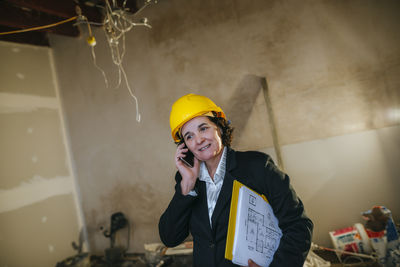 Woman wearing hard hat talking on phone on construction site