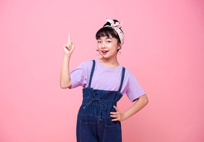 Portrait of happy woman standing against pink background