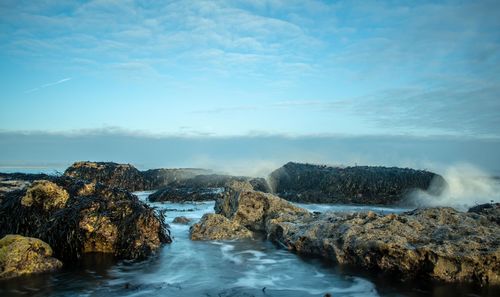 Scenic view of rocks in sea against sky