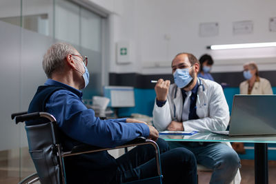 Doctor wearing mask talking with patient in clinic