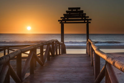 Pier over sea against clear sky during sunset