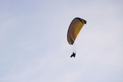 Low angle view of man paragliding against sky