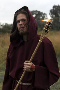 Portrait of man holding flaming torch in forest