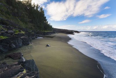 Wild beach with volcanic rocks at reunion island with a blue sky