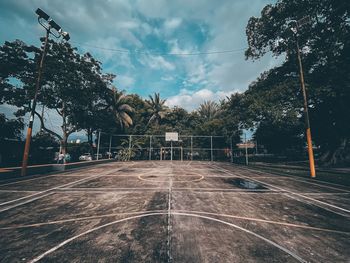 Empty road amidst trees against sky