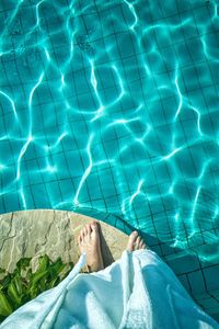 Low section of man relaxing in swimming pool