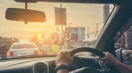 Man driving car in city during sunset