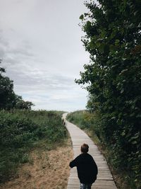 Rear view of man on footpath against sky
