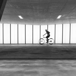 Blurred motion of man riding bicycle on footpath in tunnel