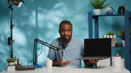 Portrait of man using laptop while sitting on table