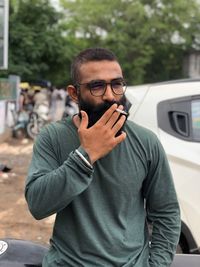 Bearded man smoking cigarette while standing outdoors