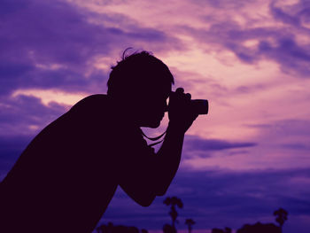 Silhouette photographer against purple sky during sunset