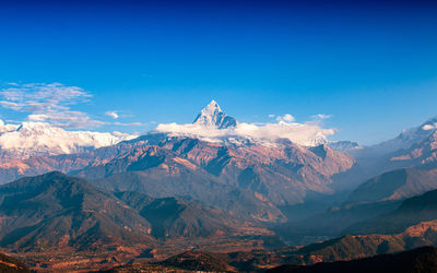 Scenic view of snowcapped mountains against blue sky