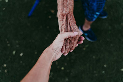 Close-up of person holding senior adult hand