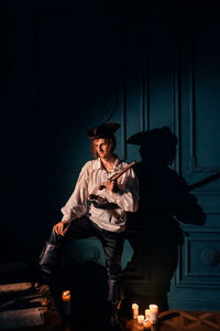 Young woman sitting on illuminated stage at night