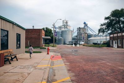 Rear view of boy running on footpath against factory at milligan