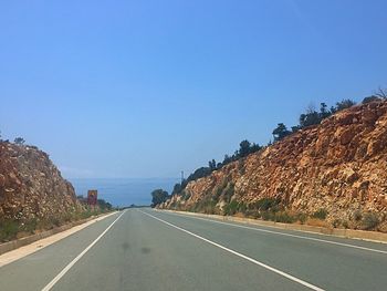 Road by mountains against clear blue sky