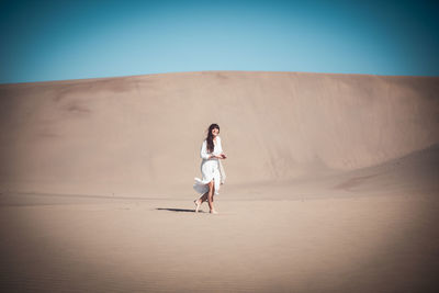 Full length of woman on sand dune against sky