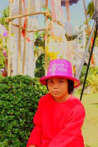 Portrait of cute girl wearing hat with text while sitting outdoors