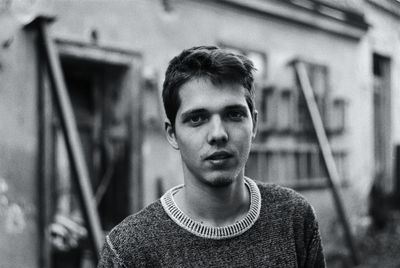 Portrait of young man standing against building