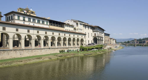 Buildings by river against clear sky