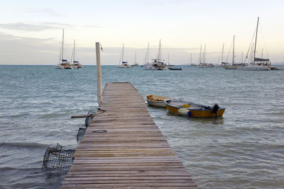 Sailboats moored in sea against sky