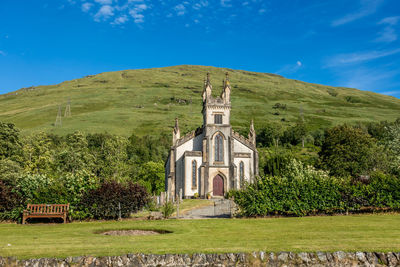 Built structure on grassy field by building against sky