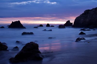 Rocks on sea against sky during sunset