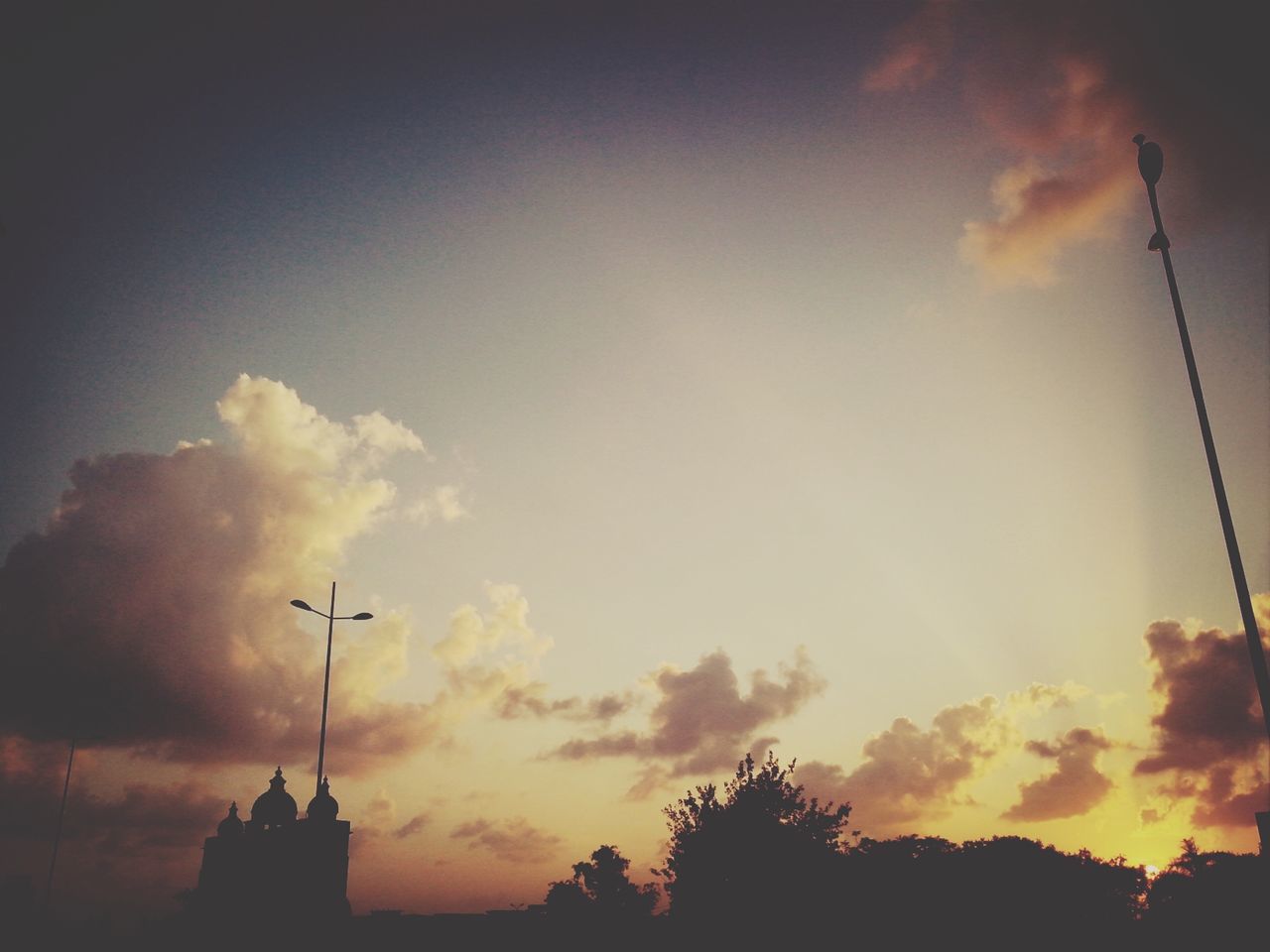 silhouette, sunset, sky, low angle view, cloud - sky, built structure, building exterior, orange color, beauty in nature, architecture, cloudy, cloud, nature, street light, scenics, dusk, tree, outdoors, dramatic sky, high section