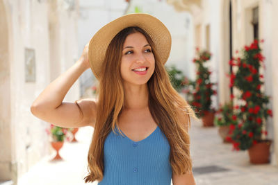Smiling young woman standing against building