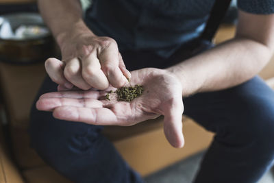 Man holding marijuana while sitting at home