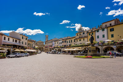 Street amidst buildings in town against blue sky