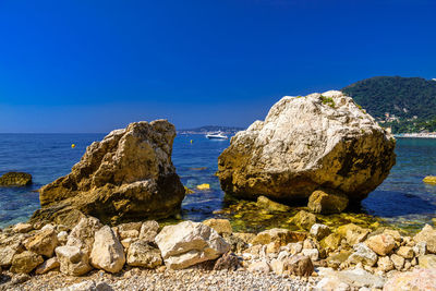 Rocks on beach against clear blue sky