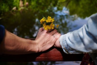 Close-up of couple's hands holding flower