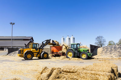 Machinery working near agricultural buildings