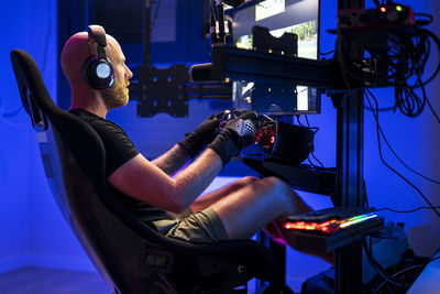 Male gamer wearing headphones while playing video game at studio