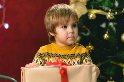 Close-up of cute boy holding christmas present at home