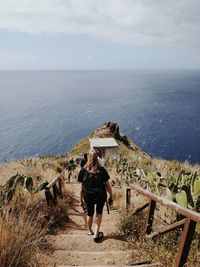 Rear view of people walking on stairs at beach against sky