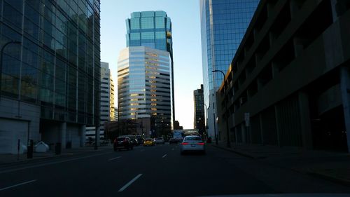 Cars on city street against sky