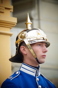 Low angle view of security guard in uniform looking away while standing against building