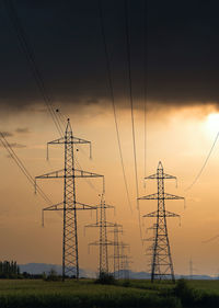 Low angle view of electricity pylon against sky during sunset