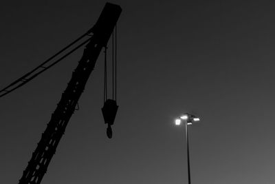 Low angle view of crane against clear sky at night