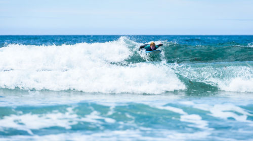 Man surfing in sea against sky