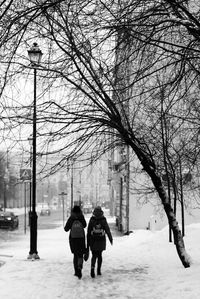 Rear view of people walking on snow covered city