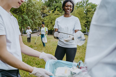 Male and female environmentalists picking up plastic waste in park