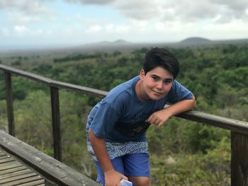 Portrait of smiling teenage boy standing on footbridge