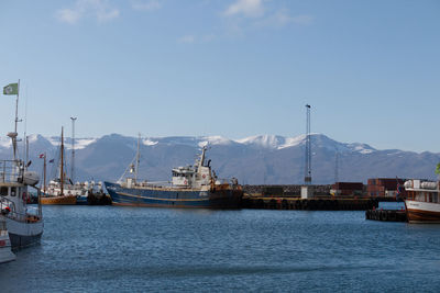 Boats moored at harbor against sky during winter