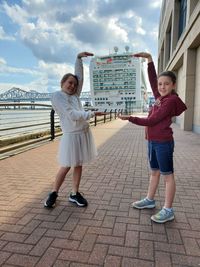 Full length of women standing on footpath against sky