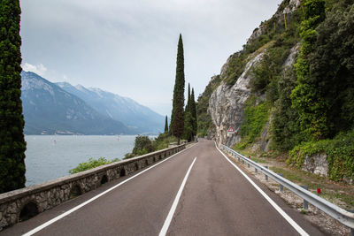 Empty road by mountains against sky