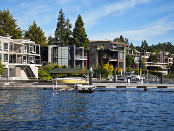 Houses by river against sky